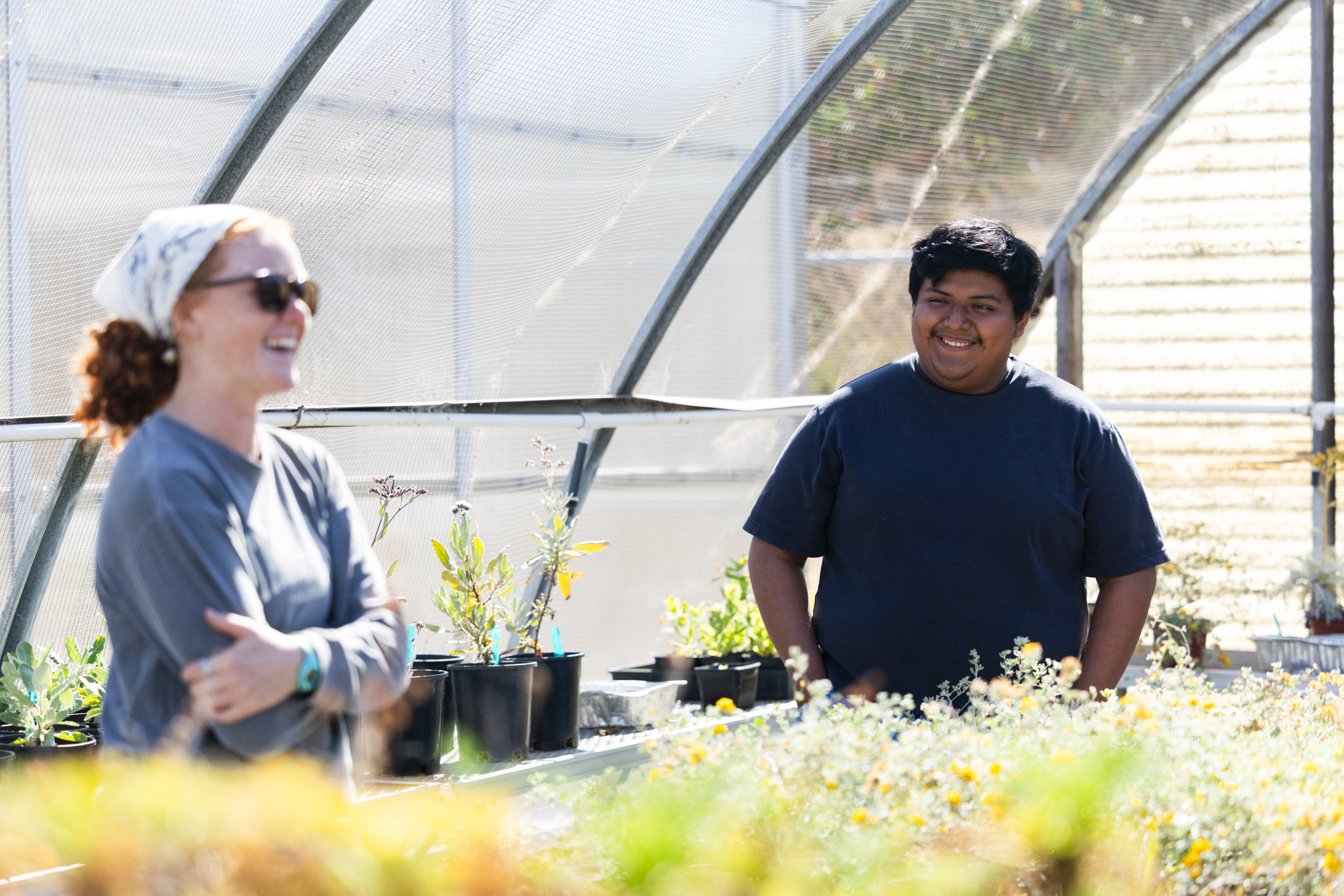 Two people laugh together inside a plant nursery